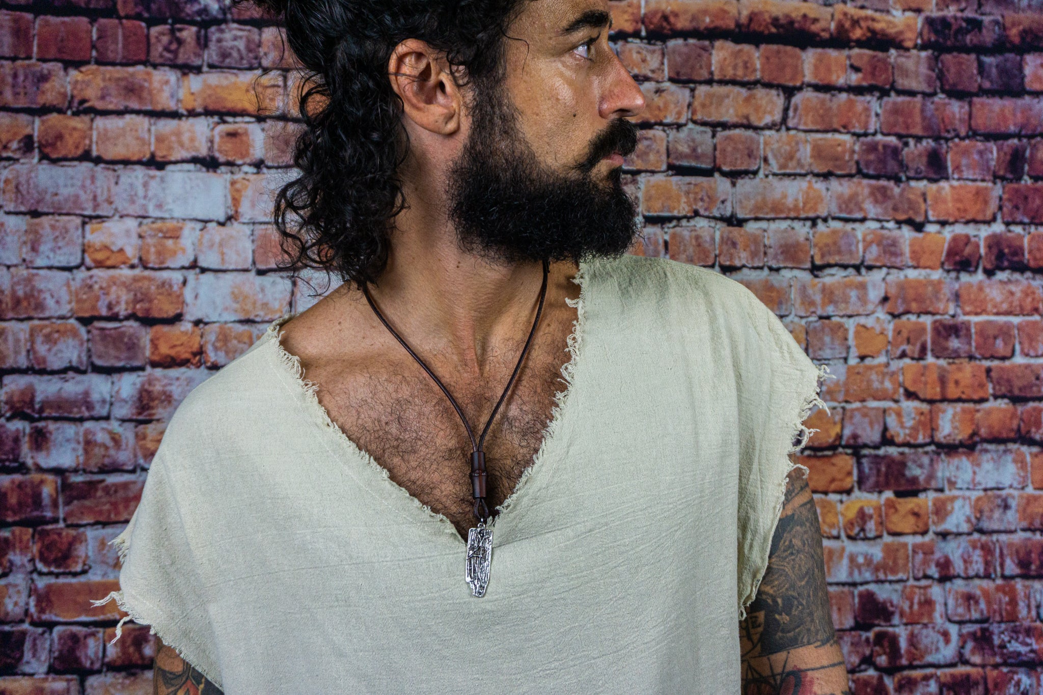 men wearing a long chunky leather necklace with a silver colored abstract pendant and a bamboo bead